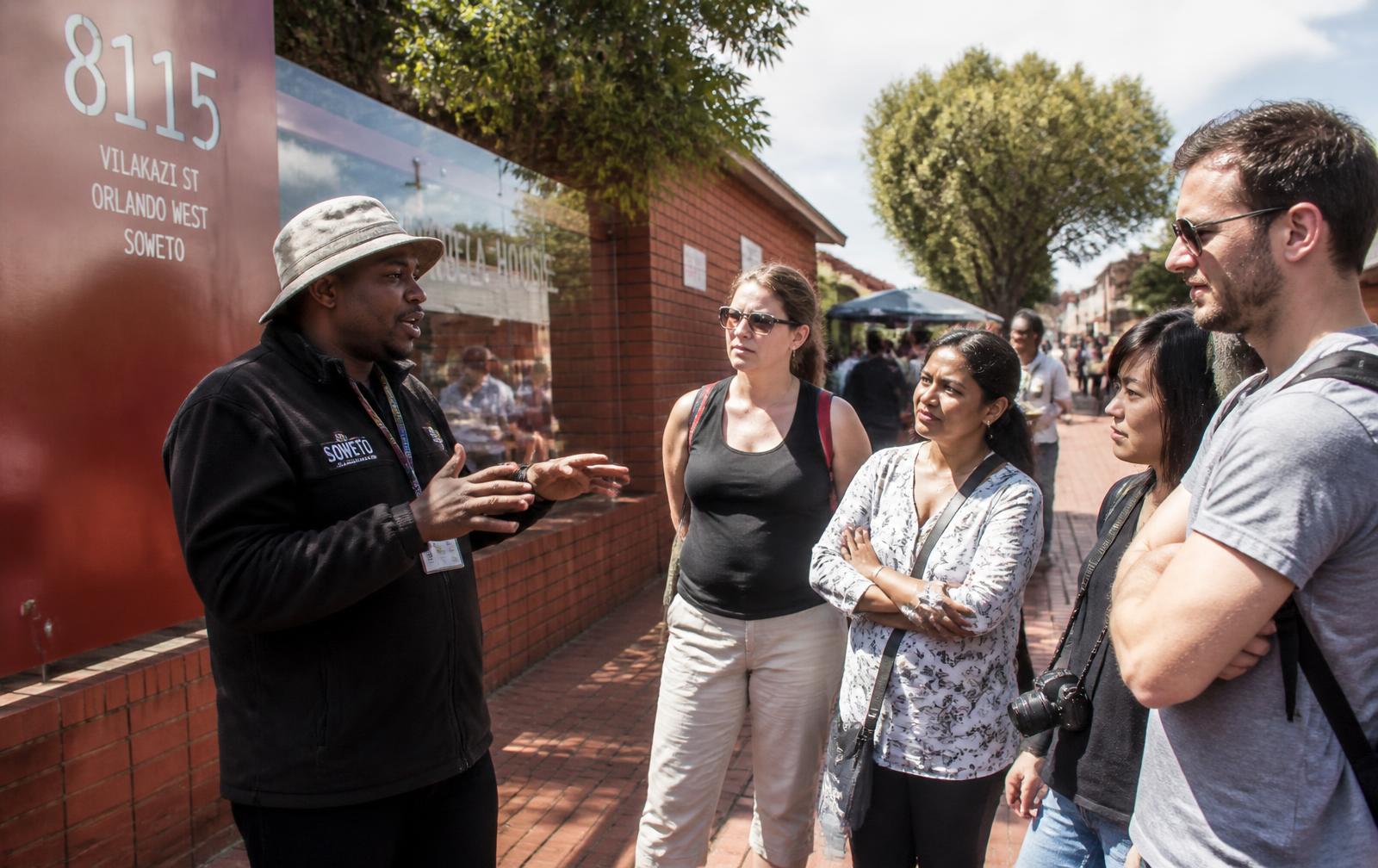 A community guide sharing local history with visitors on Vilakazi Street in Soweto